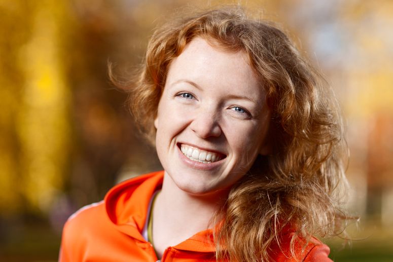 Smiling redhead poses in orange shirt.