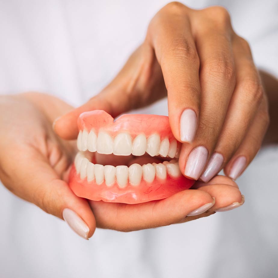 Pair of hands holding model of teeth